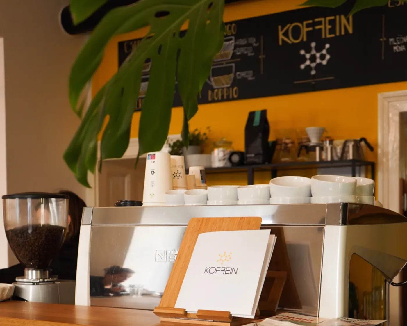 Bar kavárny Koffein se žlutou stěnou a kávovarem